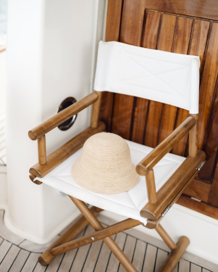Silla de madera con asiento blanco y sombrero de paja en el interior de un barco tradicional