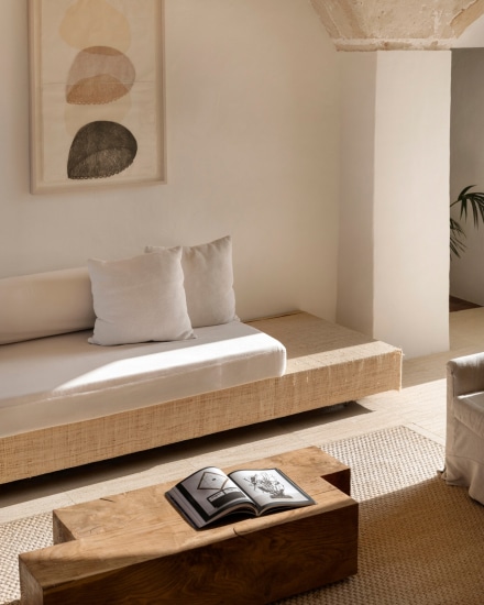 Zona de estar interior con banco corrido, cojines y mesa baja de madera