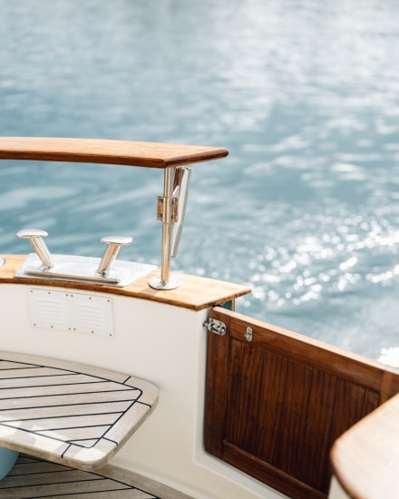 Detalle de la popa de un barco de madera con el reflejo del sol sobre el mar de Menorca