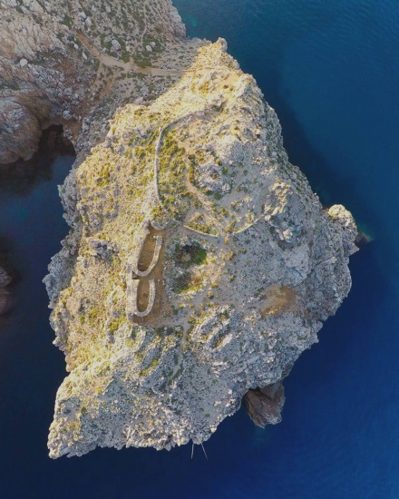Vista aérea de un promontorio rocoso junto al mar durante la ruta de los talayots en Menorca