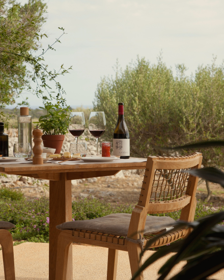Mesa exterior de la Albenc Suite con vino de Torralbenc, copas y entorno natural en Menorca
