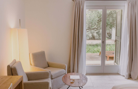 Zona de estar de la Albenc Suite con sillones, mesa auxiliar y acceso a terraza privada en Torralbenc Menorca