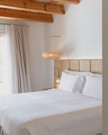 Dormitorio de la habitación Garden Cottage con cama doble, cabecero de fibras naturales y vigas de madera en Torralbenc Menorca