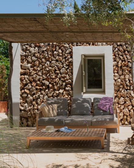 Terraza exterior de la habitación Garden Cottage con sofá, mesa baja y muro de piedra