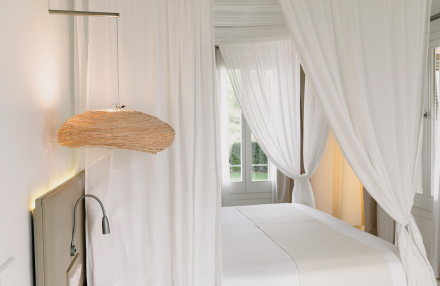 Detalle de la cama con dosel y cortinas blancas en la habitación Gran Vista Mar de Torralbenc