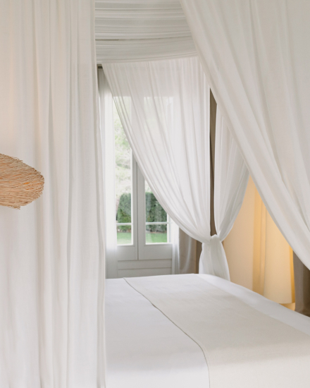 Detalle de la cama con dosel y cortinas blancas en la habitación Gran Vista Mar de Torralbenc