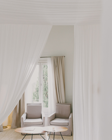 Zona de estar de la habitación Gran Vista Mar con butacas, cortinas blancas y luz natural
