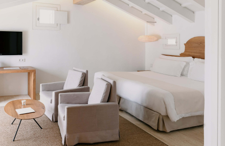 Zona de estar de la Suite Superior en Torralbenc con sillones tapizados y mesa de madera