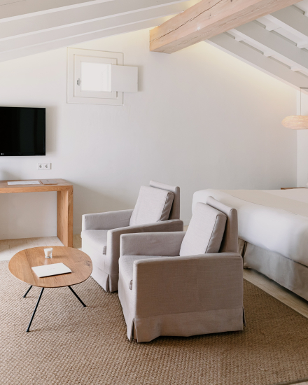 Zona de estar de la Suite Superior en Torralbenc con sillones tapizados y mesa de madera