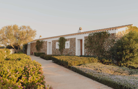 Fachada de las Suites Superiores en Torralbenc con muros de piedra y vegetación autóctona