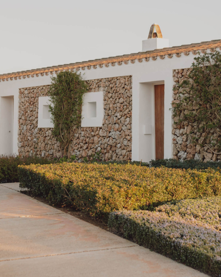 Fachada de las Suites Superiores en Torralbenc con muros de piedra y vegetación autóctona