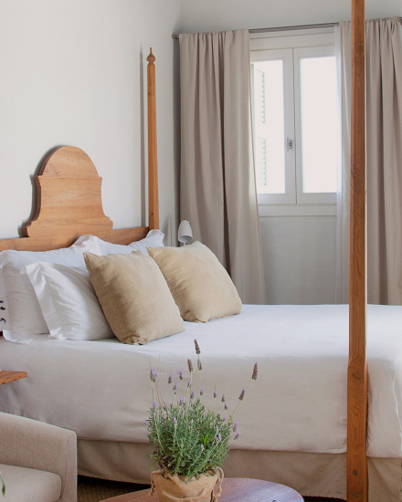 Dormitorio de la habitación Vista Mar en Torralbenc, con cama doble, cabecero de madera y decoración mediterránea en tonos neutros