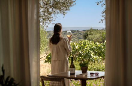 Persona contemplando la vista al mar desde Torralbenc con una copa de vino