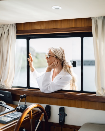 Mujer en el exterior de un barco observando el interior a través de la ventana