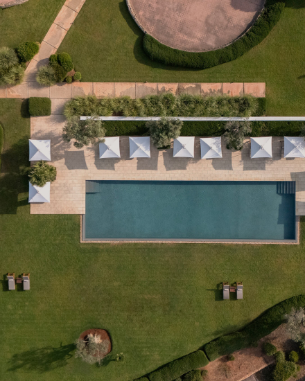 Vista aérea de la piscina de Torralbenc rodeada de jardines mediterráneos en Menorca