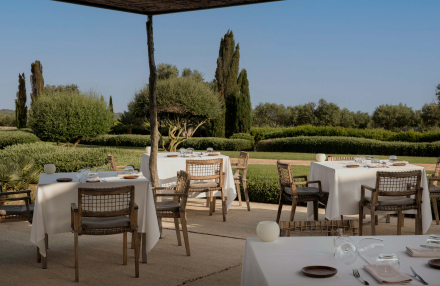Terraza exterior del restaurante Torralbenc con mesas al aire libre rodeadas de jardines mediterráneos en Menorca