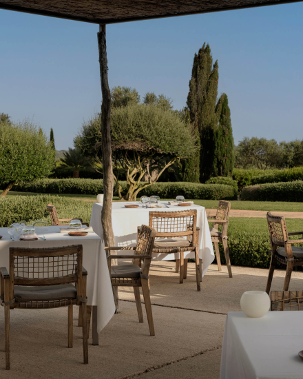 Terraza exterior del restaurante Torralbenc con mesas al aire libre rodeadas de jardines mediterráneos en Menorca
